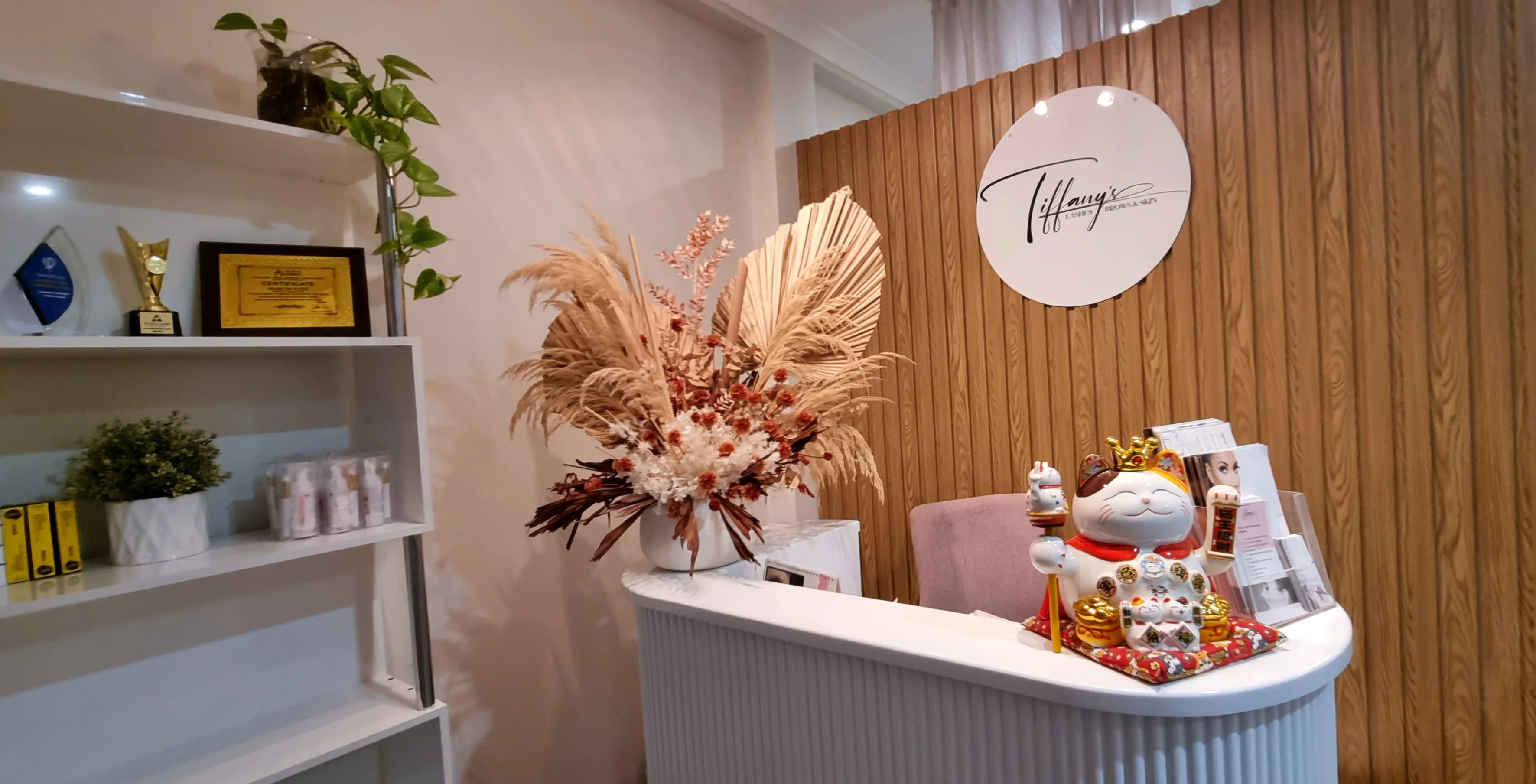Tiffany's reception — circular branded wall sign, dried pampas florals, awards shelf and retail display
