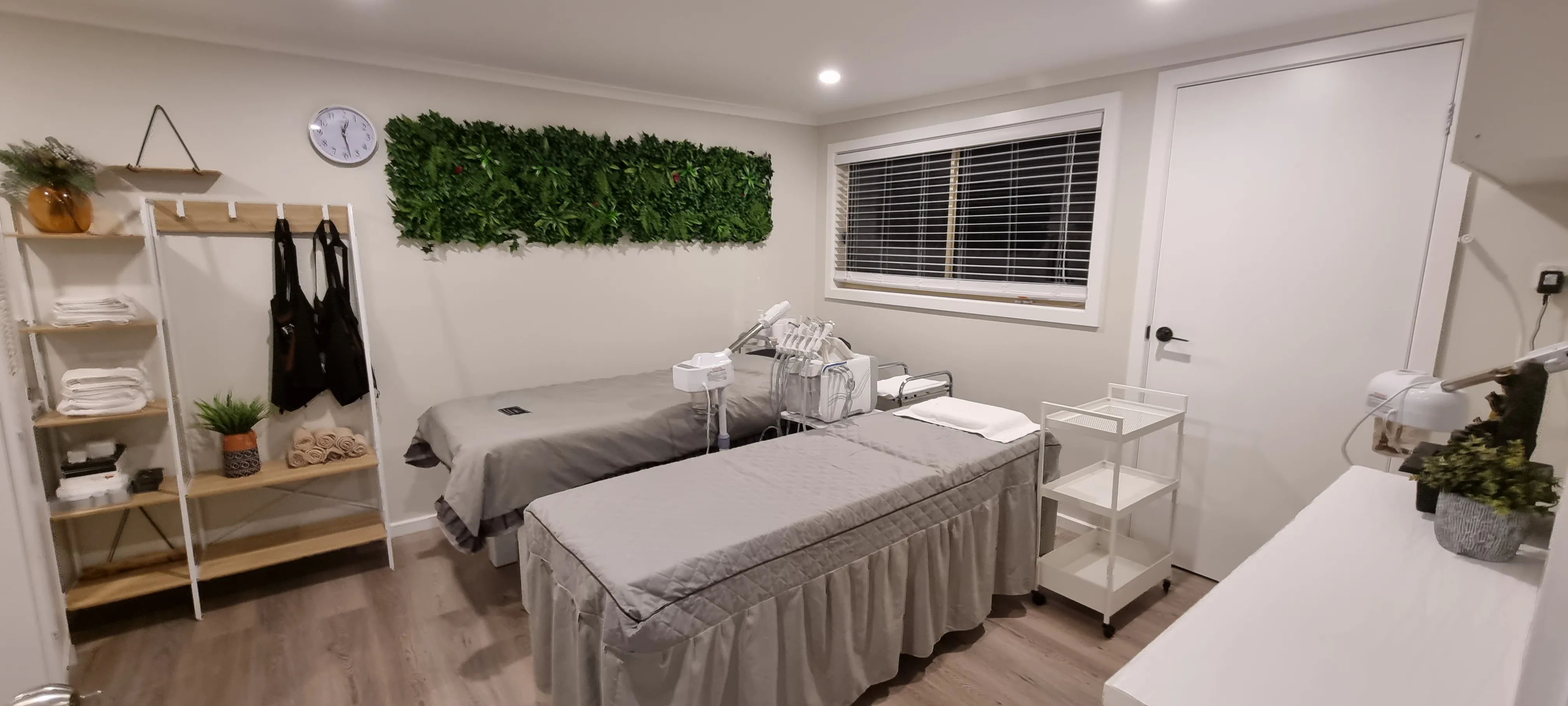 Treatment room — dual grey beds, living-green wall panel, folded towels