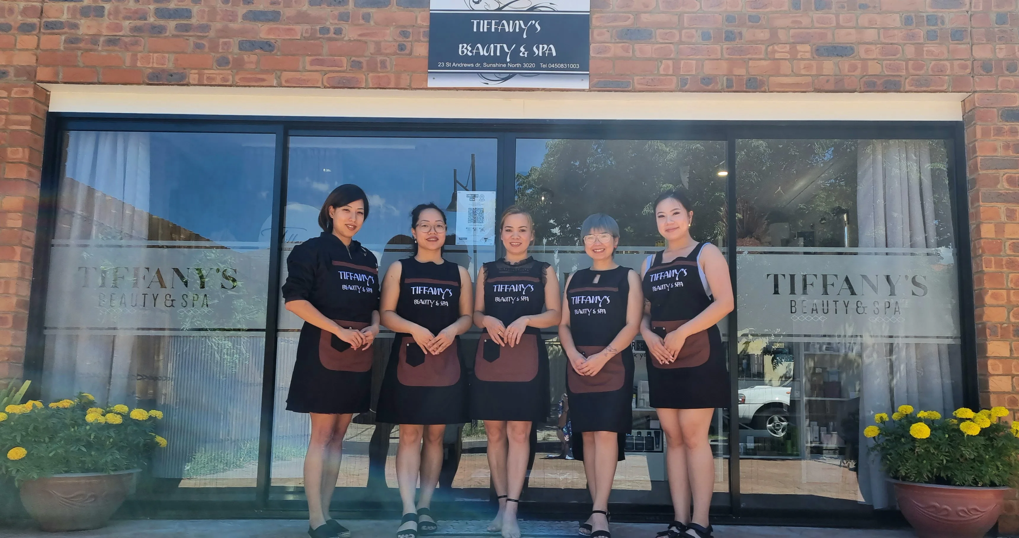 Tiffany's Beauty & Spa team in matching branded aprons outside the storefront